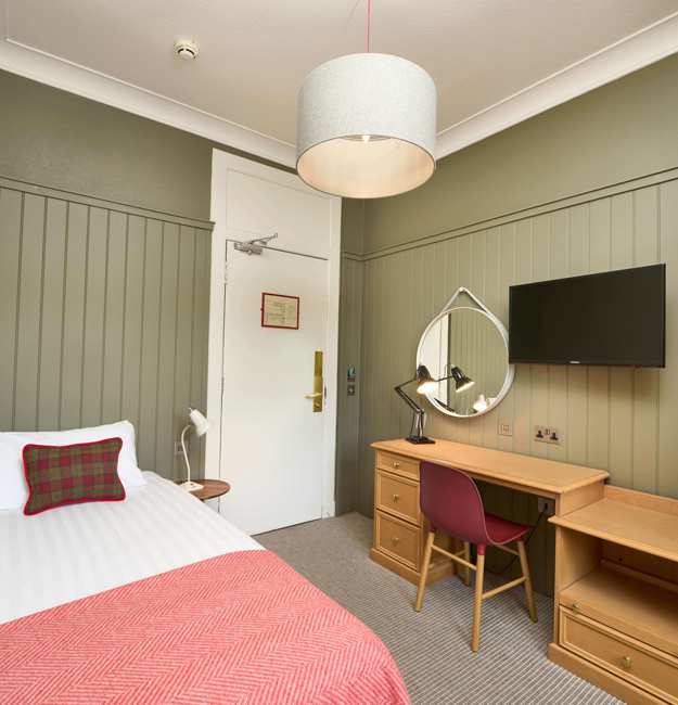 Room with single bed, bedside table, vanity unit, TV, and wardrobe